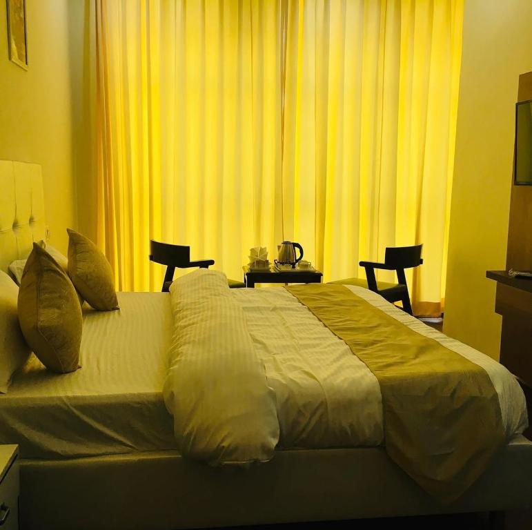 1 dormitorio con 1 cama grande y cortinas amarillas en The venture, en Zirakpur