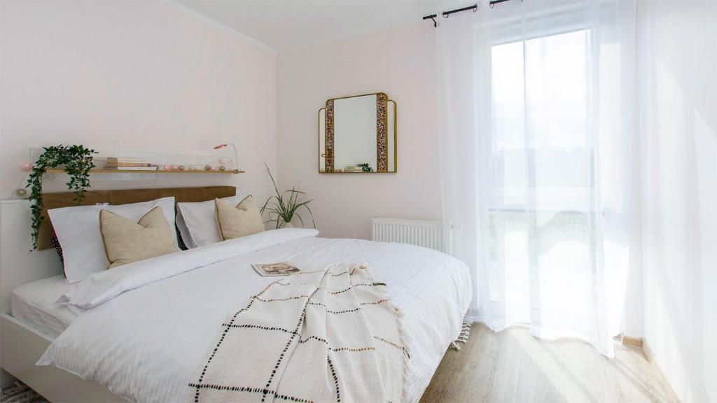 a bedroom with a white bed with a mirror and a window at Baltic Line - Sobieszewski Raj in Gdańsk