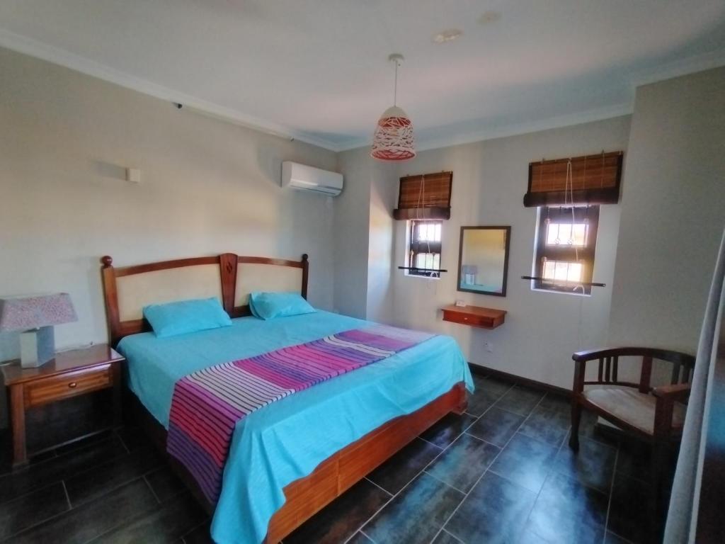 a bedroom with a bed and a chair and windows at Villa Azalea in Grand Baie