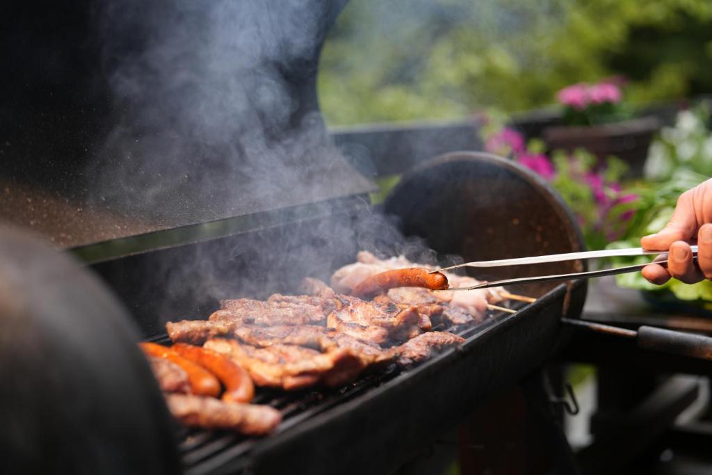 a person cooking meat on a grill with tongs at Mladenović Kuća in Kopaonik