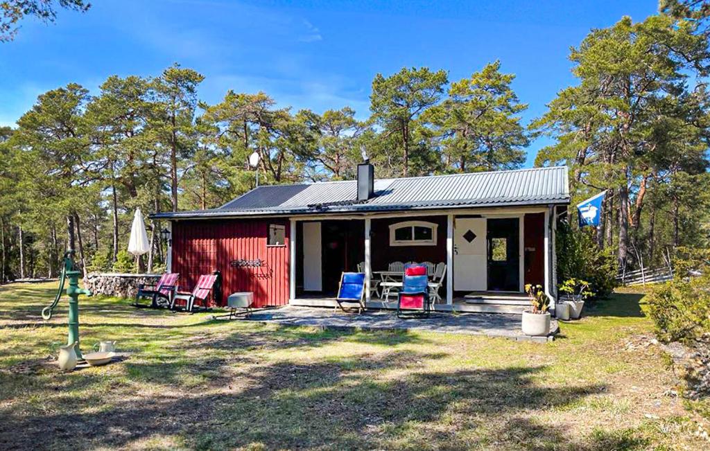 a red house with chairs and a dog in front of it at 3 Bedroom Cozy Home In Tingstäde in Tingstäde