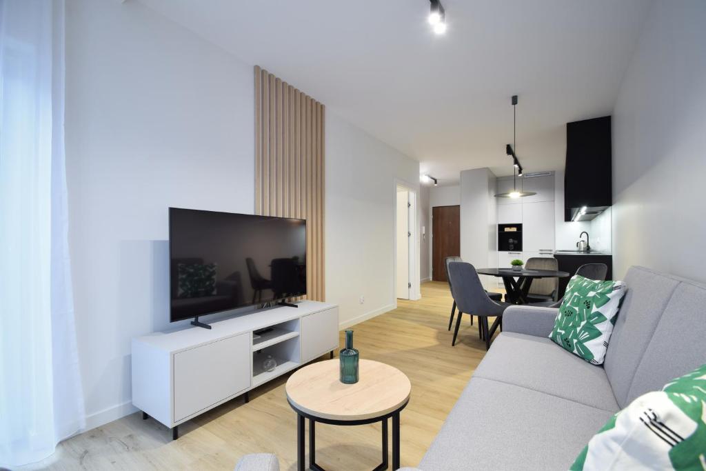 a living room with a couch and a flat screen tv at Apartament Szmaragd&Perła by LookAp - parking gratis! in Poznań
