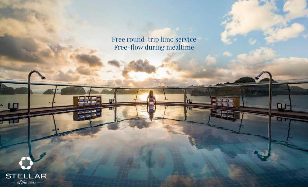 a woman standing on the edge of a pool with the sunset at Stellar of the Seas Cruise in Ha Long