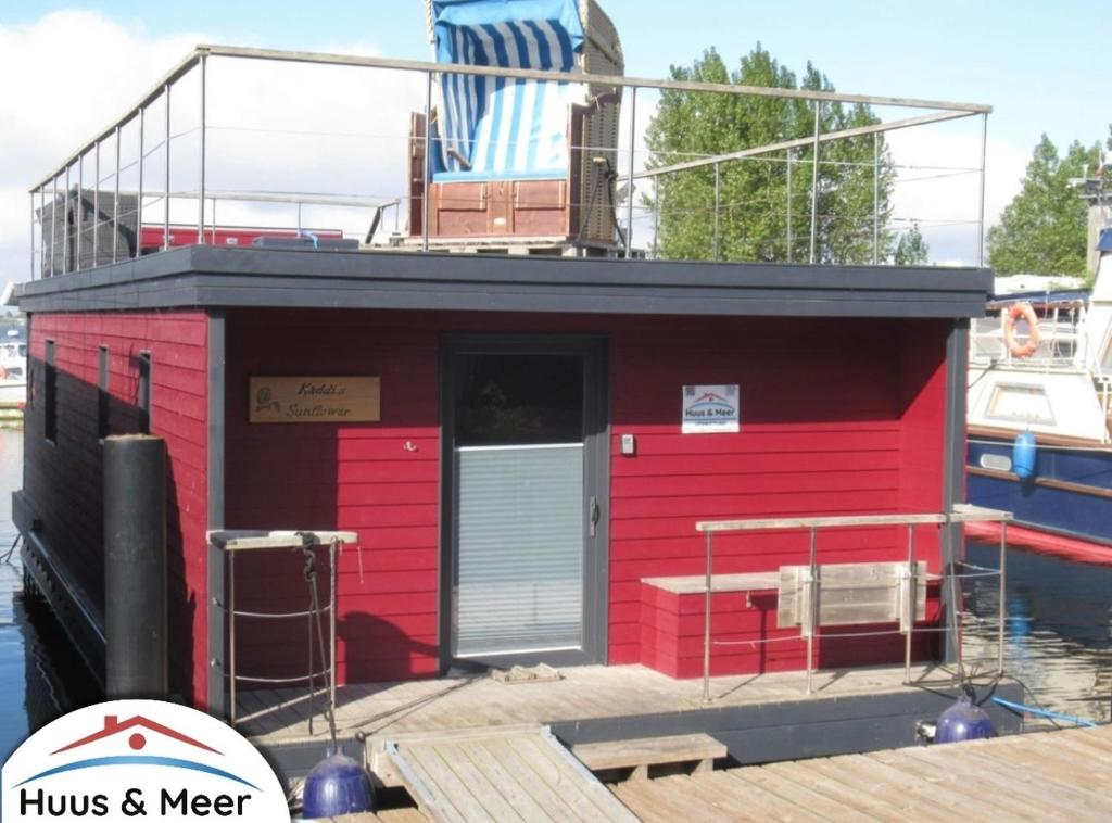 un edificio rojo encima de un barco en Hausboot Kaddi`s Sunflower - Huus & Meer, en Burgstaaken