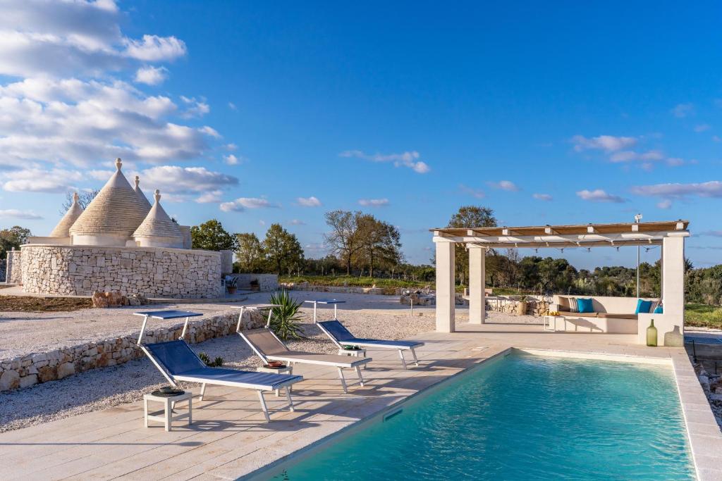 une piscine avec des chaises longues et une pergola dans l'établissement Trullo The Cove, à Ceglie Messapica