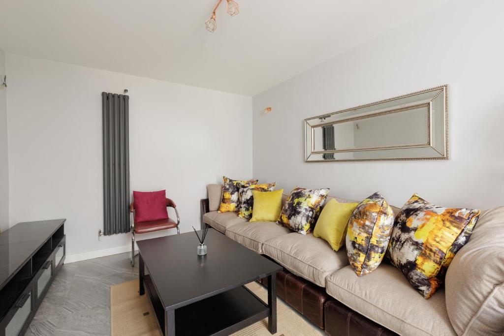a living room with a couch and a mirror at 2-Bed Flat with Free Parking by Lee Valley Park in Enfield
