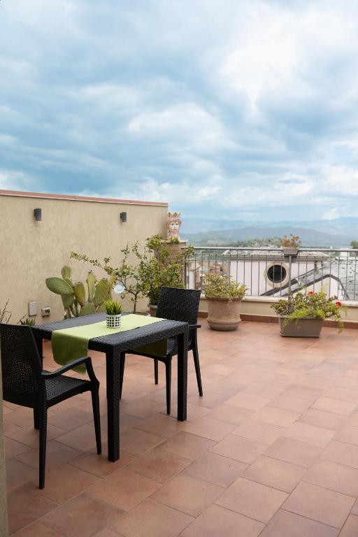 patio ze stołem i krzesłami na dachu w obiekcie B&B Bella Vista w mieście Valguarnera Caropepe