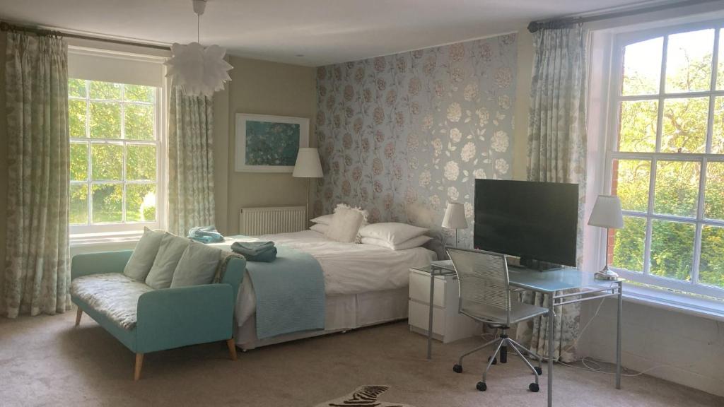 a bedroom with a bed and a desk and a tv at Lingwood Hall in Lingwood