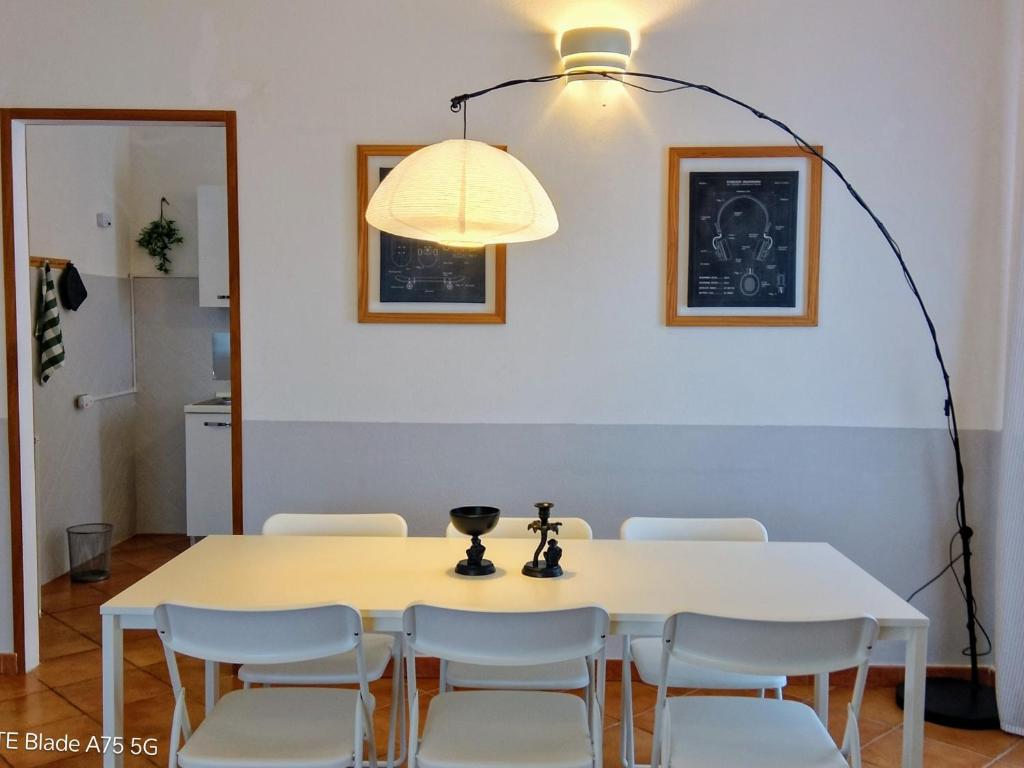 a dining room table with white chairs and a light fixture at Appartamento in villa Porto Pollo in Porto Pollo
