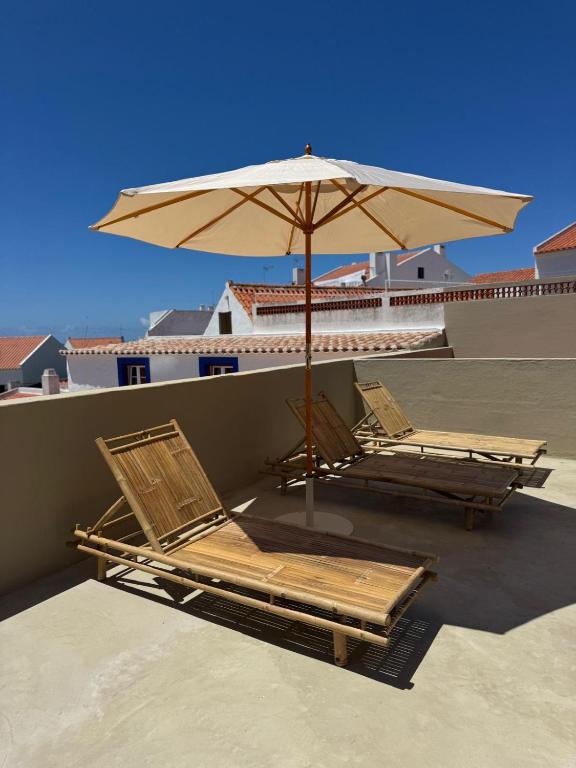 two lounge chairs and an umbrella on a roof at Vila Laura in Porto Covo