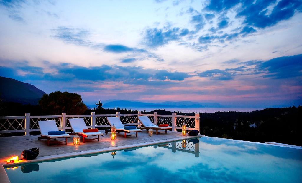 a swimming pool with lounge chairs and a sunset at Castello Di Vista in Kato Korakiana