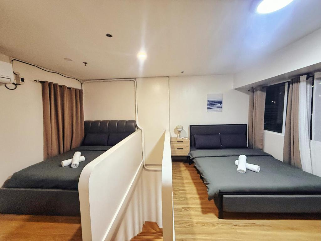 a bedroom with two beds and a stair case at Family Loft Unit Hotel in BGC The Fort High Street in Manila