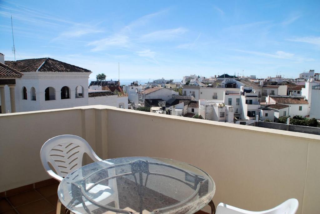 a glass table and chairs on a balcony with a view at Apartamentos Plaza in Nerja