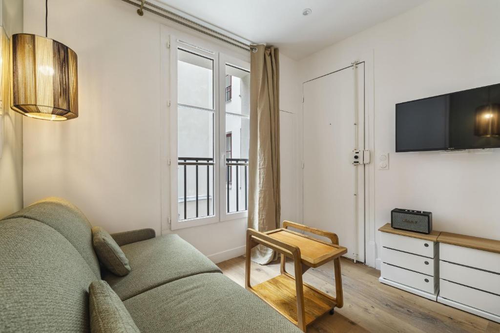 un salon avec un canapé et une télévision dans l'établissement Lordino, à Paris