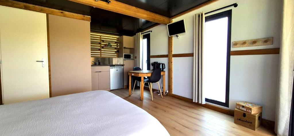 une chambre avec un lit et une table et une cuisine dans l'établissement La Luna - Tiny House Spa - Romantique & Nature, à Saint-Yan