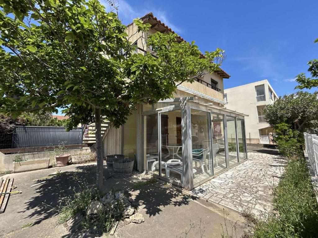 une maison en verre avec un arbre en face de celle-ci dans l'établissement NP480-034 Appartement 3 pièces, Narbonne Plage, à Narbonne-Plage