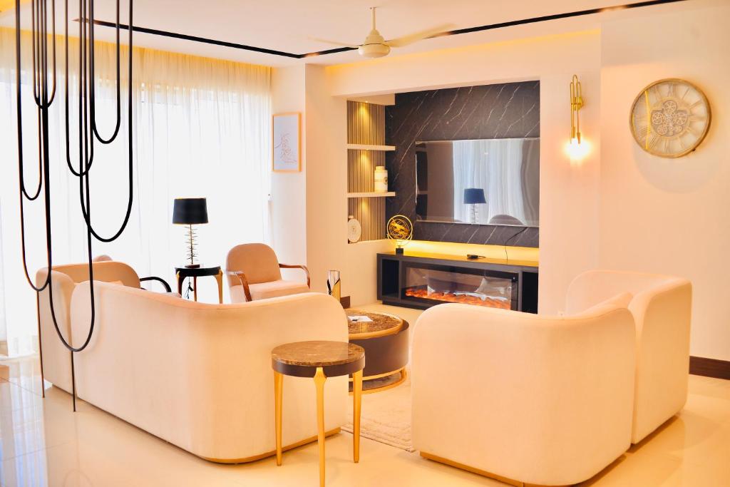 sala de estar con sillas blancas y chimenea en Splendor Penthouse By Stayvia, en Karachi