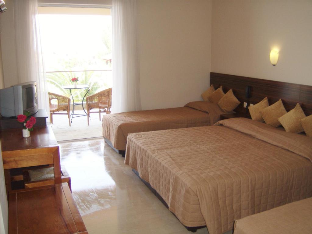 a hotel room with two beds and a television at Thea Hotel in Possidi