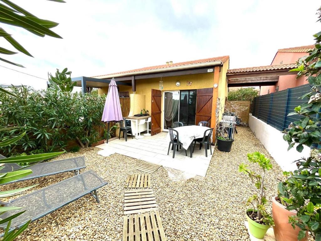 une arrière-cour avec une table et des chaises ainsi qu'une maison dans l'établissement Pavillon Beau Soleil à Narbonne Plage, à Narbonne-Plage
