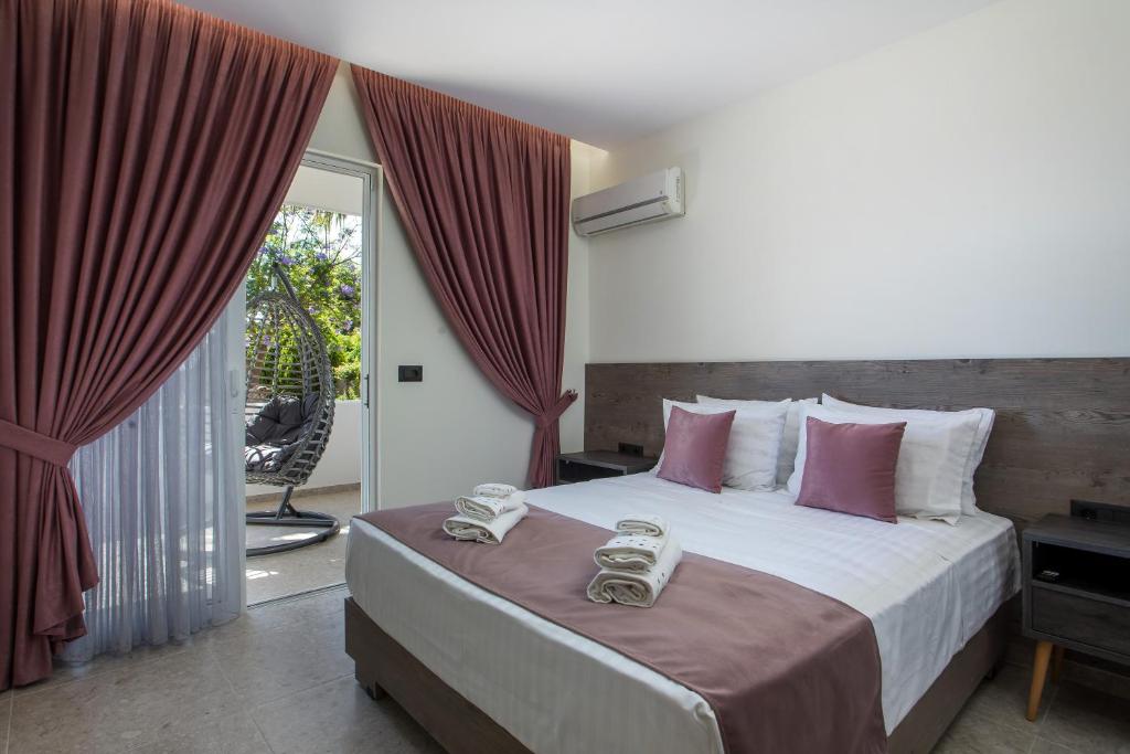 a bedroom with a large bed with red curtains at Matsi Suites in Faliraki