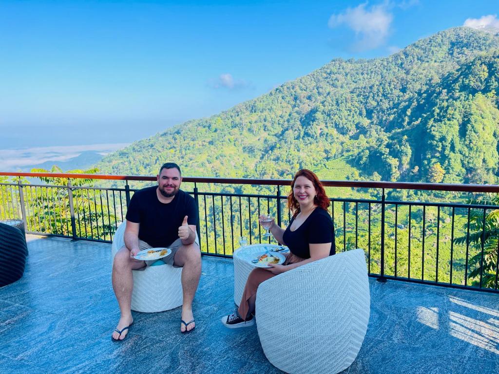 a man and woman sitting on a balcony with plates of food at Kavi s Hideaway in Dedugala