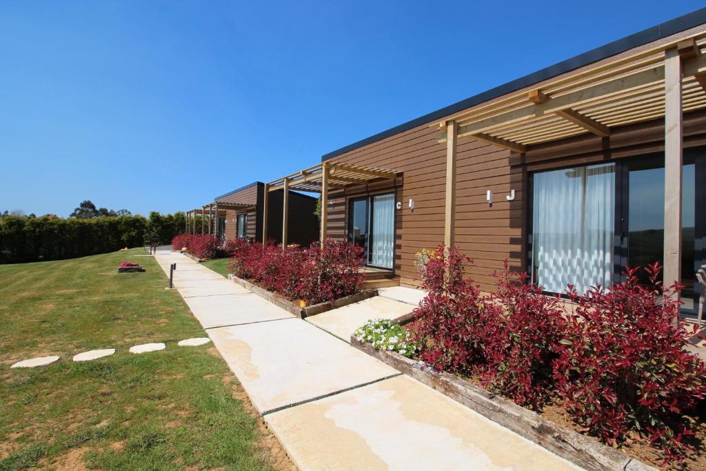 un bâtiment avec des plantes rouges à côté d'un trottoir dans l'établissement Bungalows Elma, à Suances