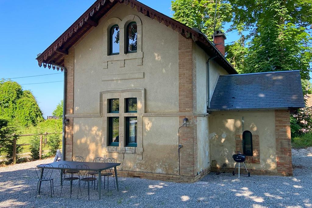 une petite maison avec une table en face dans l'établissement La maison du gardien, à Sillé-le-Philippe