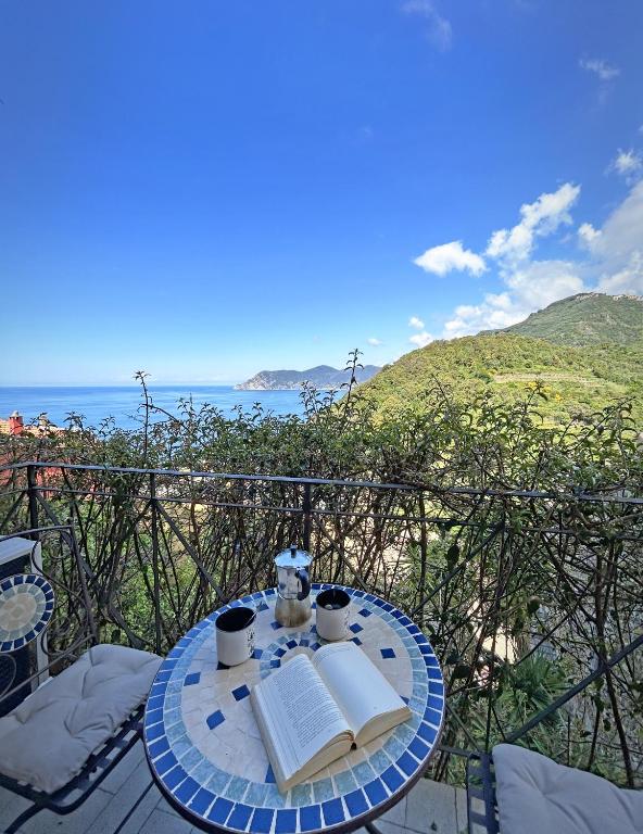 a table with two books and two cups on a balcony at Pietra Azzurra, Newly Renovated in Corniglia
