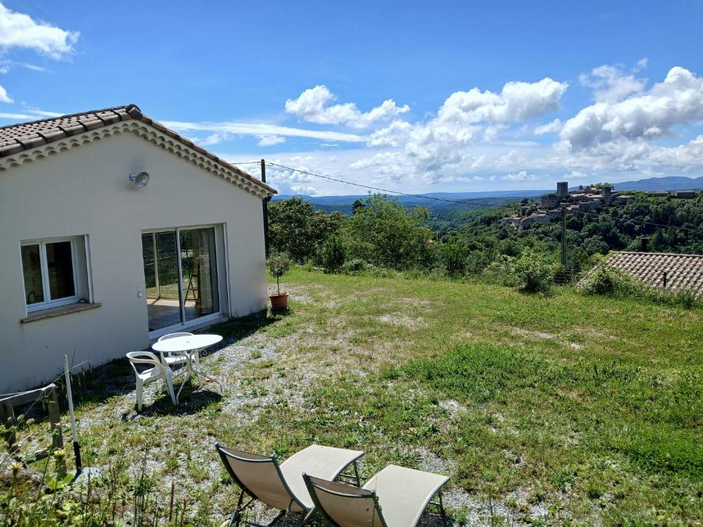 un groupe de chaises et une table dans une cour dans l'établissement Gîte Les Mimosas - 2 à 4 personnes - Vue imprenable, à Largentière