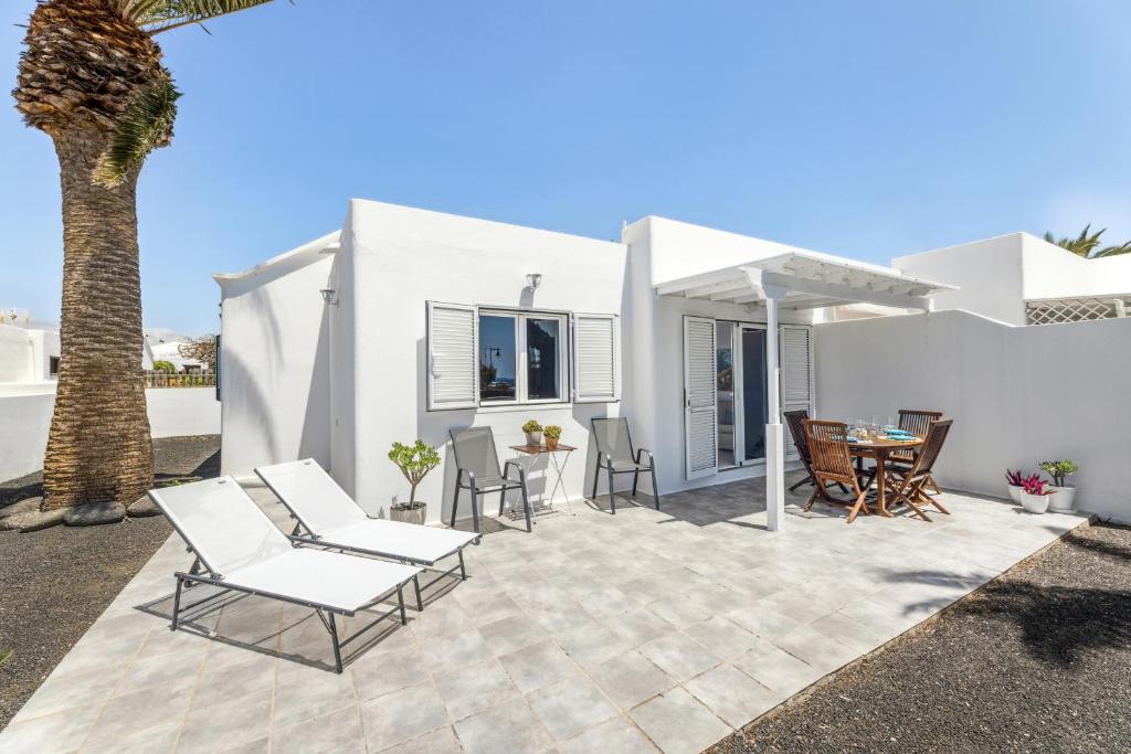 un patio con sillas, una mesa y una palmera en Casahost El Cable Seaview Beach house, en Arrecife