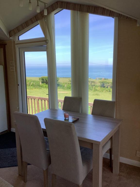 a dining room table with chairs and a view of the ocean at Meadowview in Cardigan