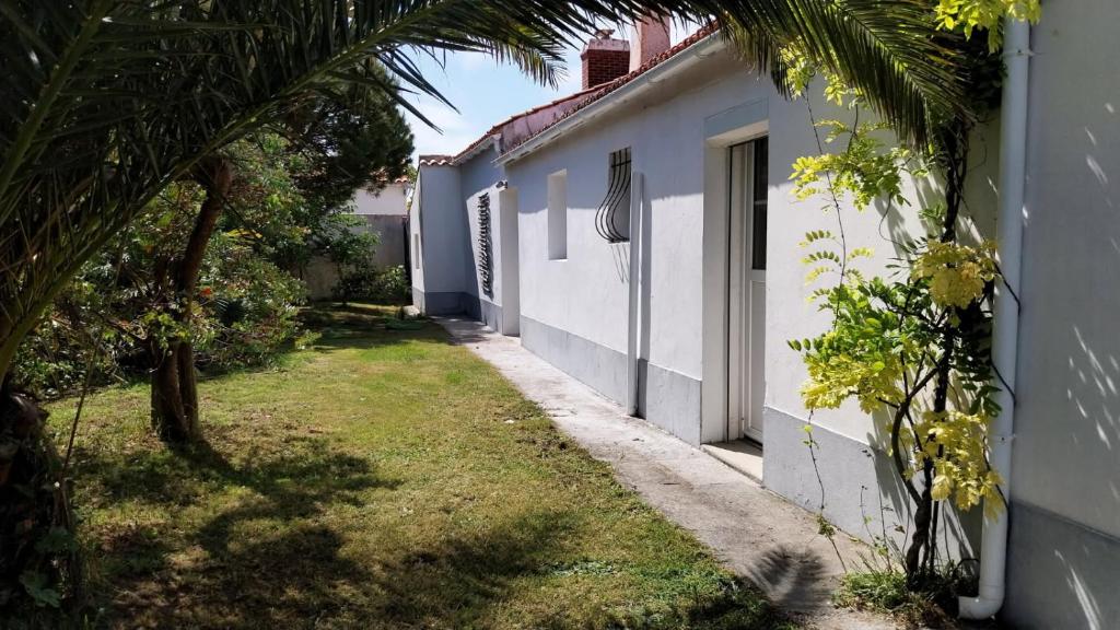 une ruelle vide avec un bâtiment blanc et des palmiers dans l'établissement Maison de vacances Ile de Noirmoutier, à LʼÉpine