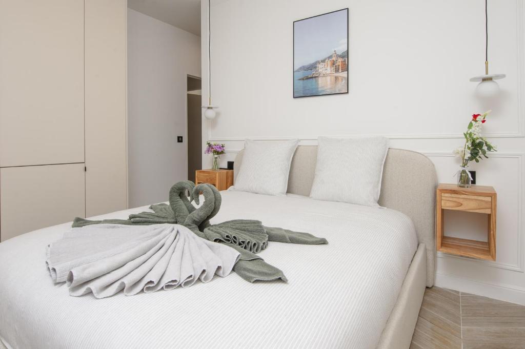 a bedroom with a white bed with a towel on it at SUITE DELUXE - MONACO - Vue Jardin in Beausoleil