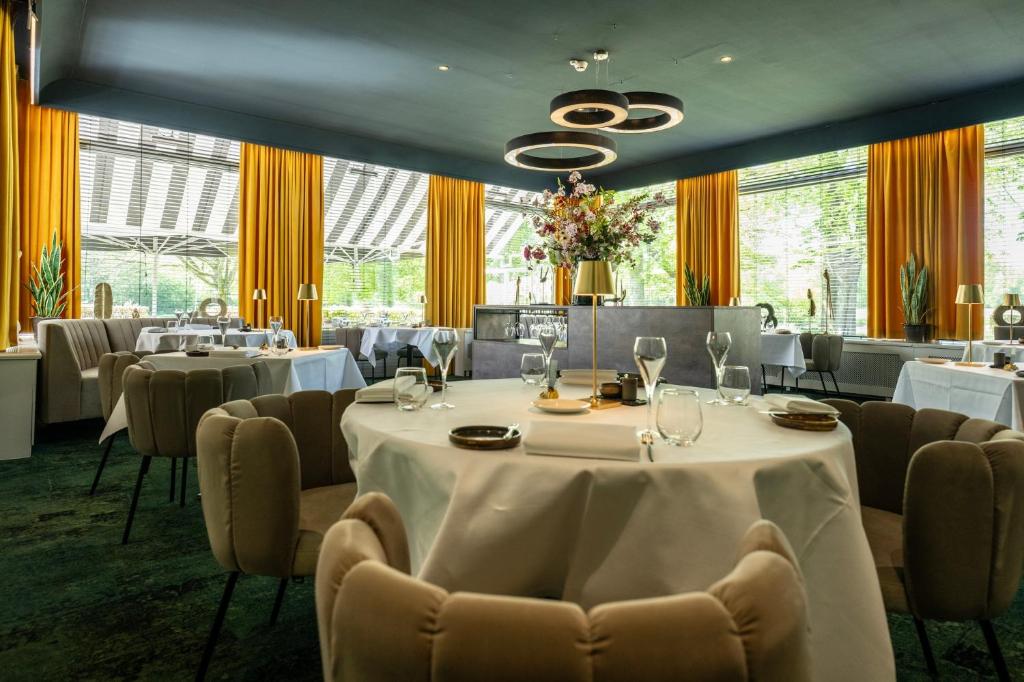 een eetkamer met tafels en stoelen en een groot raam bij Landgoed Hotel & Restaurant Carelshaven in Delden