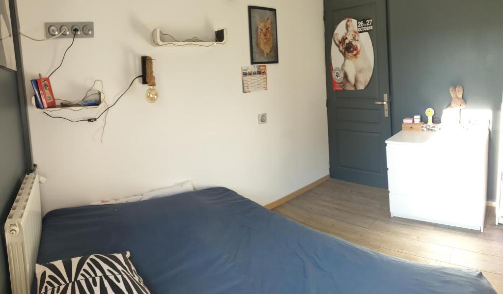 - une chambre avec un lit bleu et un réfrigérateur blanc dans l'établissement La maison autour du figuier, à Aramon