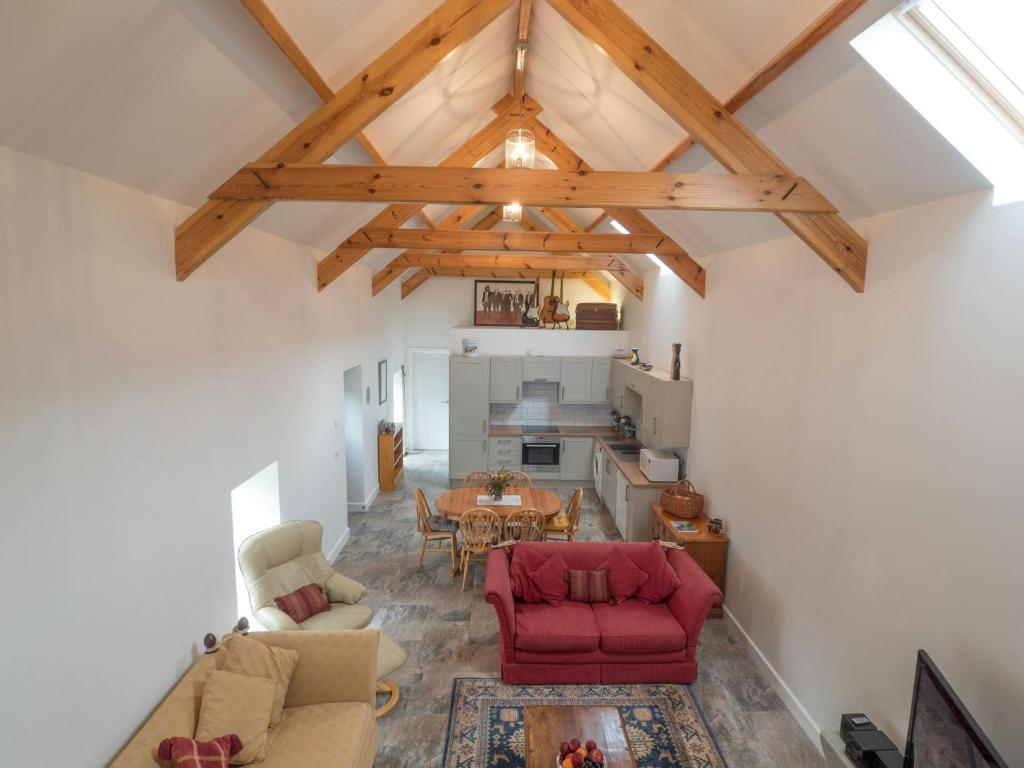 a living room with a red couch and a table at Ty Hen Farm Dairy Penbryn in Tresaith