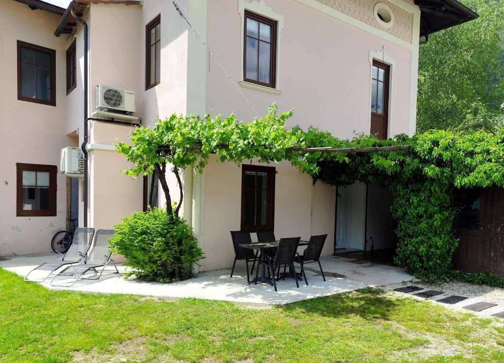 a patio with a table and chairs in front of a house at Apartment Zaklad Soče with hot tub and free parking in Bovec