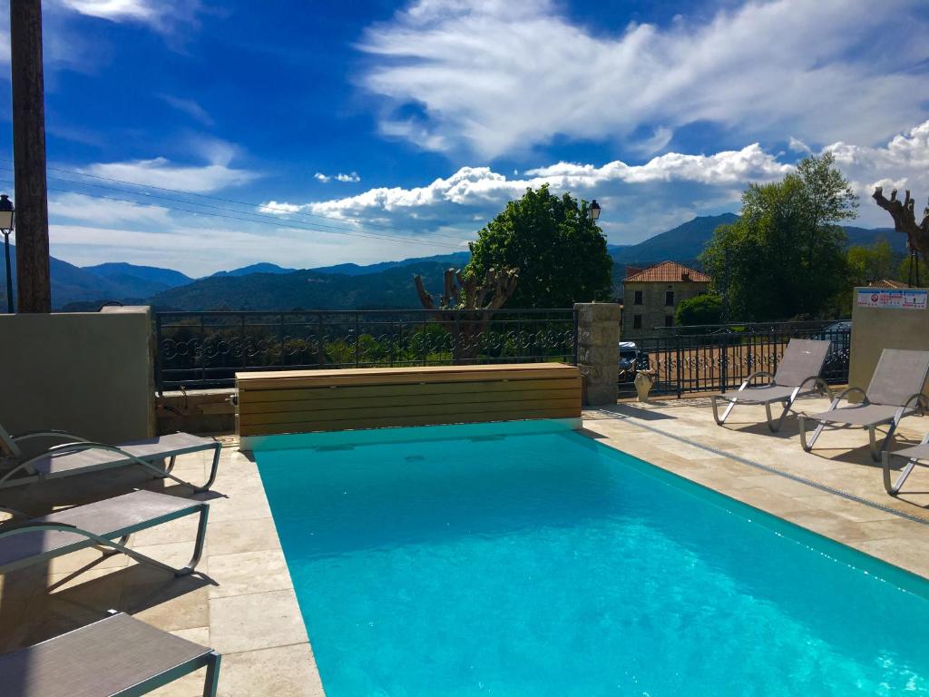 a swimming pool with chairs and a view of mountains at Hotel Clair de Lune in Zonza