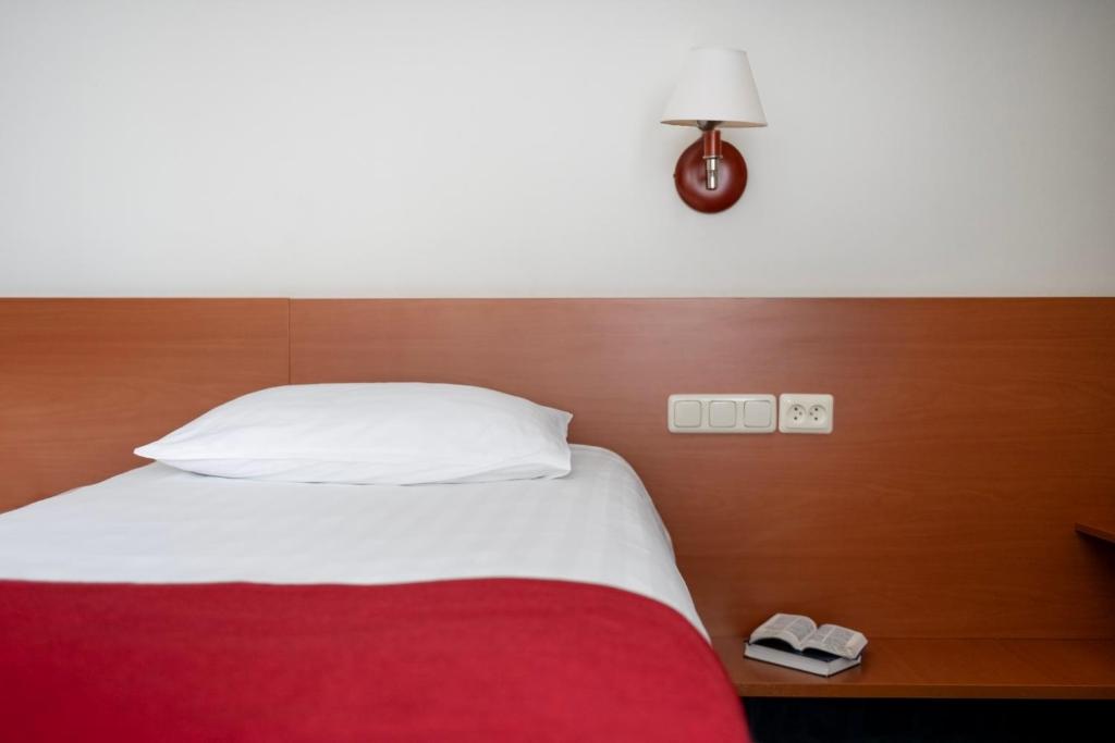 Art City Inn — A bed with a red blanket and a white pillow and a lamp