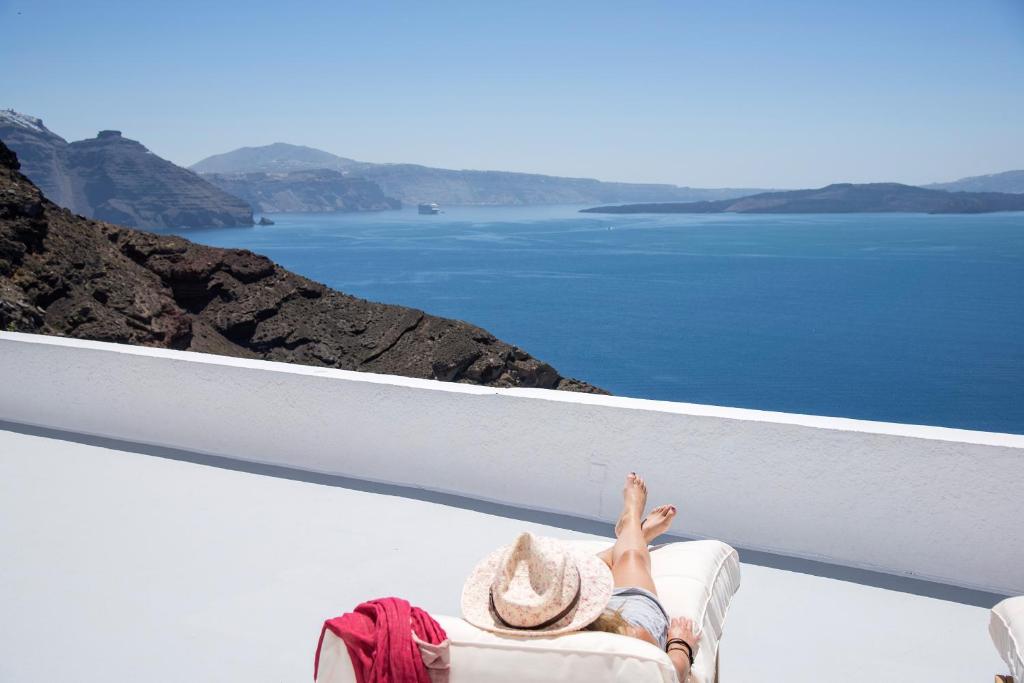 Una mujer tendida en un balcón con vistas al agua en Perfect Purity, en Oia