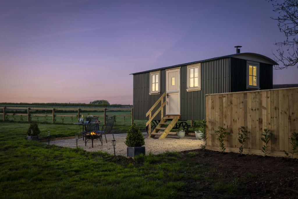 a black tiny house sitting on top of a field at The Cotswold Nest in Moreton in Marsh