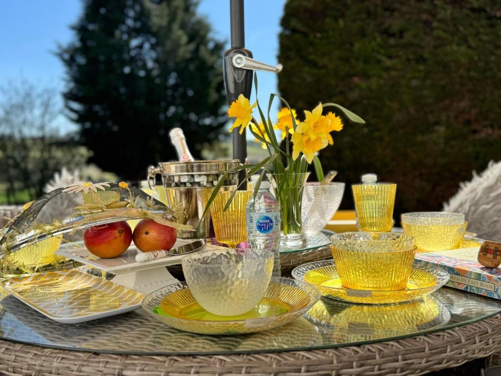 a glass table with plates and bowls of food on it at WestLaigh Central Scotland with outdoor BBQ Hut, pets welcome in Strathaven