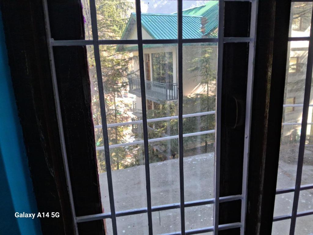 an open window with a view of a yard at Himalayan Hostel, opposite to white waterinn hotel, tipa road, mecleodganjj in Dharamshala