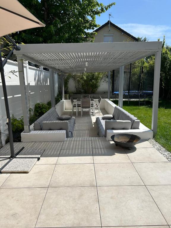 un patio avec des canapés et un parasol blanc dans l'établissement Cozy house 5min Enghien's Lake, à Enghien-les-Bains