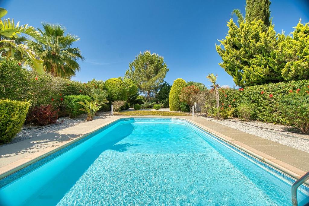 a swimming pool in a garden with trees and bushes at Eleon Villa in Kouklia