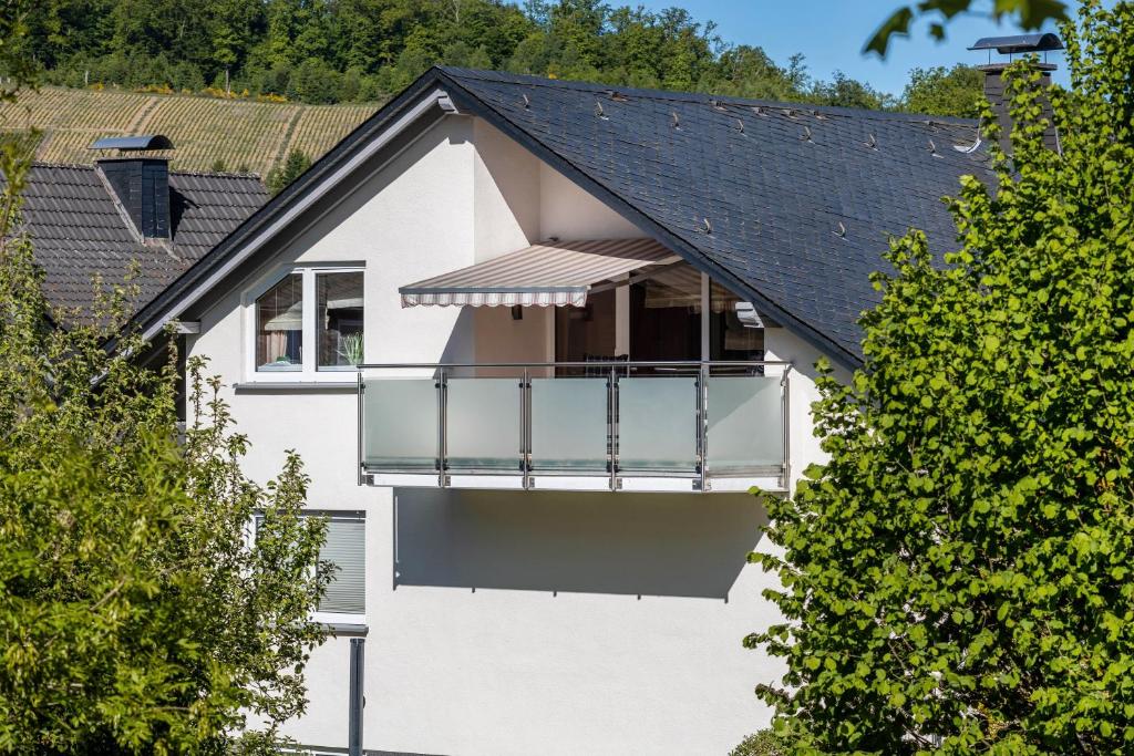 una casa blanca con balcón y árboles en Ferienwohnung Urban, en Bestwig