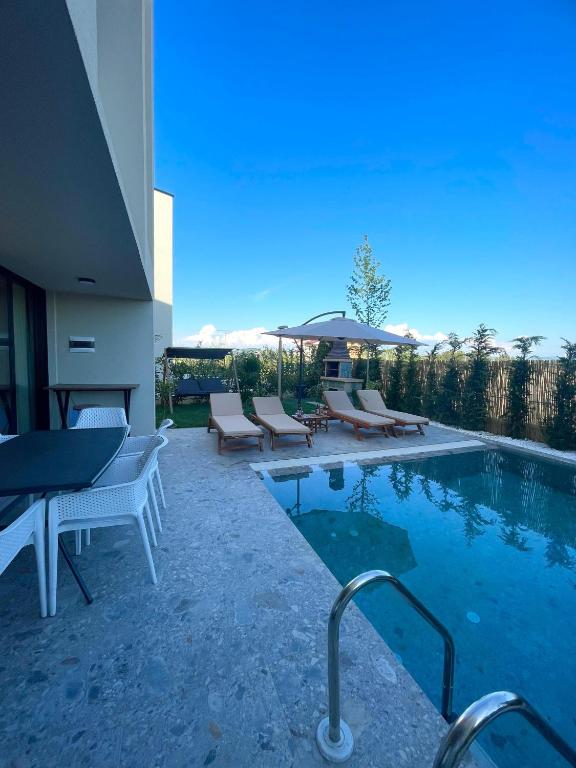 a swimming pool with lounge chairs next to a house at Pearl Pool Luxury Villa in Golem