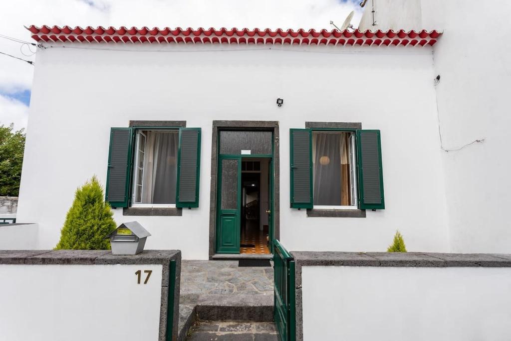 une maison blanche avec des volets verts et une porte dans l'établissement GuestReady - Furnas Nest, à Furnas