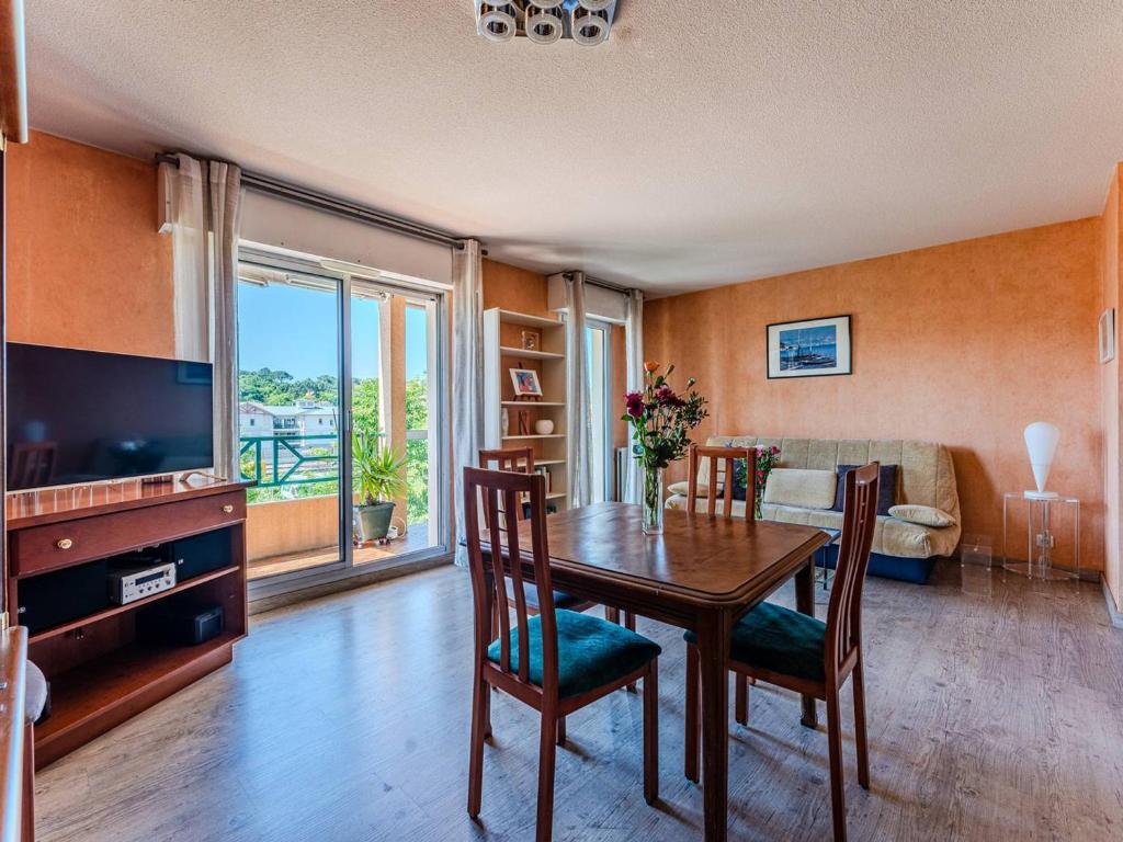 un salon avec une table à manger et une télévision dans l'établissement Appartement T2 à Arcachon avec balcon, parking sécurisé, proche gare SNCF et commerces - FR-1-433-32, à Arcachon