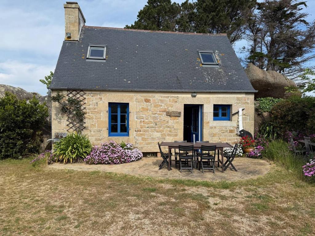une table et des chaises devant une maison en pierre dans l'établissement Maison Bretonne à 50m de la Plage avec Jardin, WIFI et Vélos - Trégastel - FR-1-368-27, à Trégastel